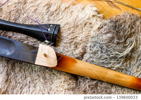 Broken contrabass neck joint with fingerboard and tailpiece on felted wool locks rug. Close up 139600033