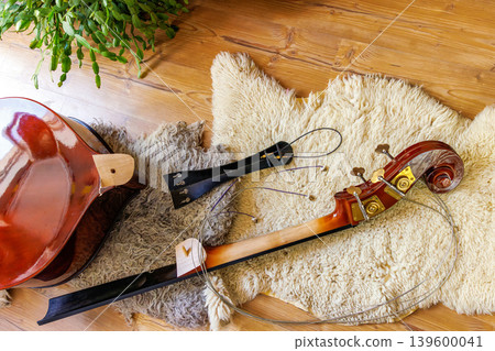 Broken contrabass body and detached neck, fingerboard and scroll on wool blanket with loose strings 139600041