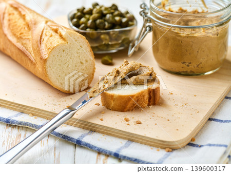 Sliced baguette with pate from the liver, on a white wooden table, selective focus. 139600317