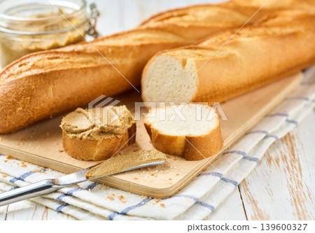 French bread baguette with liver pate curls on a kitchen table, selective focus. French bread baguette with liver pate curls on a kitchen table, selective focus. 139600327