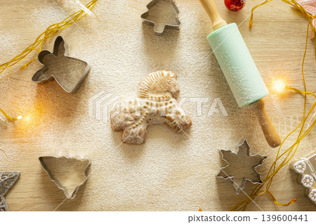 A horse-shaped gingerbread on a table with flour and a rolling pin. Baking Christmas cookies. Christmas background A horse-shaped gingerbread on a table with flour and a rolling pin. Baking Christmas cookies. Christmas background 139600441