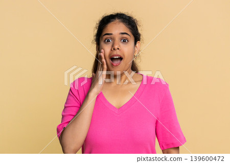 Indian woman with shocked expression, eyes wide open and hands on face isolated on beige background 139600472
