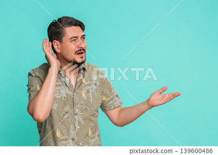 Adult man trying hear you looking confused and frowning, keeping arm near ear for louder voice 139600486