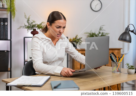 Young businesswoman faces laptop freeze presses keyboard no response shows despair and hold head Young businesswoman faces laptop freeze presses keyboard no response shows despair and hold head 139600515