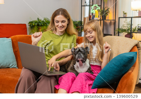 Mother daughter dog win game on laptop get positive test result celebrate good news smile together Mother daughter dog win game on laptop get positive test result celebrate good news smile together 139600529