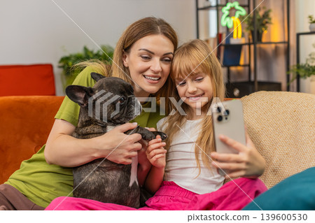 Mother daughter dog selfie joke with smartphone filter mask laugh together make faces playful family 139600530