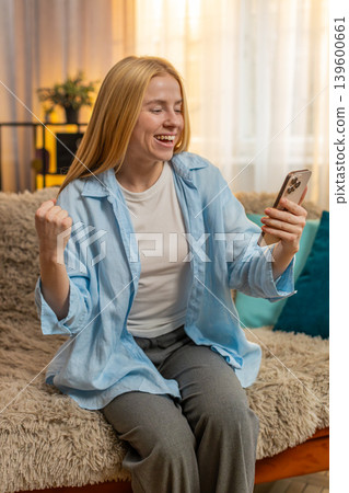 Young woman rejoicing phone success, thrilled message on smartphone, upbeat reaction, bright mood Young woman rejoicing phone success, thrilled message on smartphone, upbeat reaction, bright mood 139600661