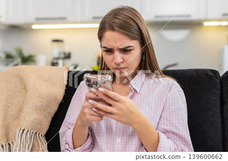 Young woman reads long work chat on smartphone facepalm types reply to resolve conflict under stress Young woman reads long work chat on smartphone facepalm types reply to resolve conflict under stress 139600662