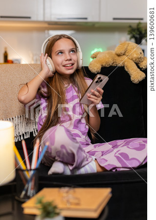 Teenager girl enjoys music with wireless headphones from smartphone smiles moves dances happy rhythm 139600681