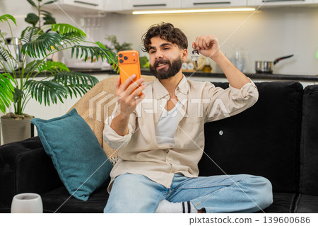 Indian man smartphone video call smiling showing apartment keys to family celebrating new life start 139600686