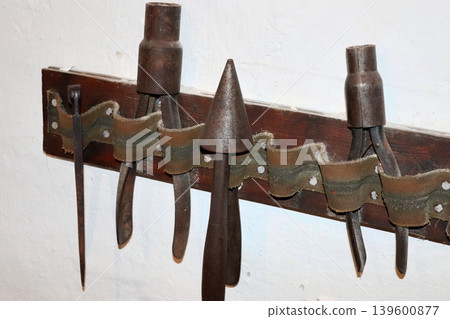 A set of tools for blacksmithing and jewelry work, mounted on the wall. 139600877