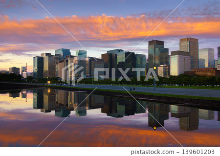Tokyo, Japan - Oct 1 2024, panoramic view of skyscrapers of Chiyoda district, with a moat in foreground with mirror-like water reflecting buildings and sky, and colorful clouds in sky at sunset, Tokyo Tokyo, Japan - Oct 1 2024, panoramic view of skyscrapers of Chiyoda district, with a moat in foreground with mirror-like water reflecting buildings and sky, and colorful clouds in sky at sunset, Tokyo 139601203