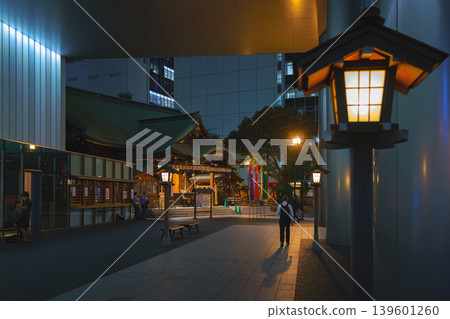 Tokyo, Japan - Oct 1 2024, A panoramic view of the Toranomono Kotohiragu Shinto shrine in the evening, with old street lamp glowing on foreground, office building on background, Tokyo, Japan  139601260