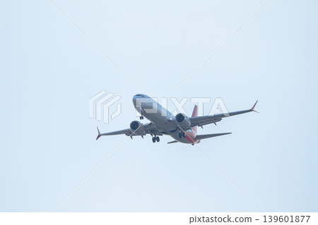 Large commercial airplane with extended landing gear descending through a muted sky for airport arrival and global transportation concepts. Large commercial airplane with extended landing gear descending through a muted sky for airport arrival and global transportation concepts. 139601877