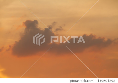 Atmospheric sunset scene with dark floating clouds over a glowing orange sky, creating a dramatic and peaceful natural background with soft evening light. Atmospheric sunset scene with dark floating clouds over a glowing orange sky, creating a dramatic and peaceful natural background with soft evening light. 139601898