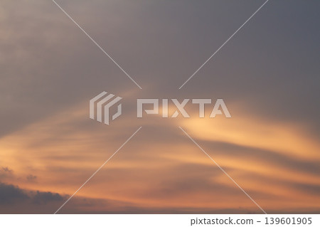 Elegant layered clouds glowing with warm sunset tones across a tranquil evening sky, creating a smooth atmospheric background with natural light gradients. 139601905