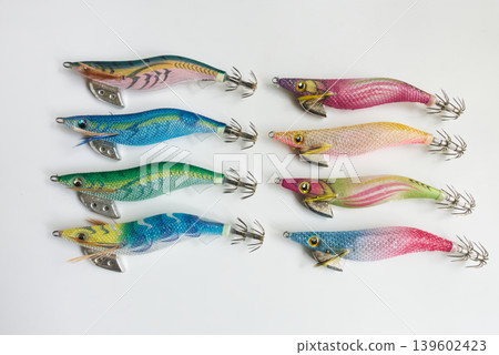 一排色彩鮮豔的魷魚鉤（egi）排列在白色背景上。 139602423