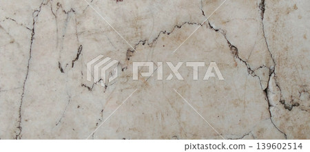 The texture of an old concrete wall with natural cracks and a dull, pale cream colored surface. 139602514