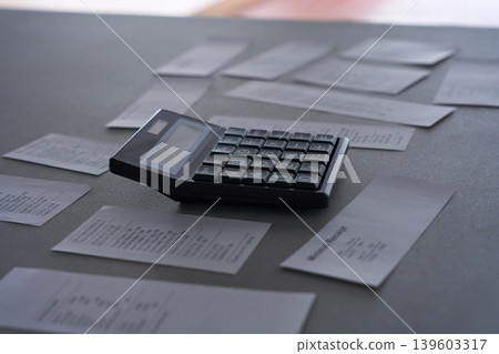 Receipts and a calculator scattered on the table 139603317