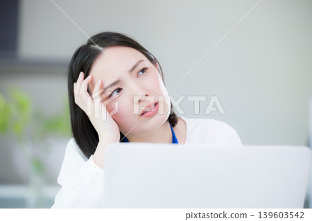 A busy office-casual woman in front of her computer, struggling with multitasking and thinking about her tasks; an image of a busy task management. A busy office-casual woman in front of her computer, struggling with multitasking and thinking about her tasks; an image of a busy task management. 139603542