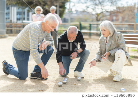 Elderly people analyzing the game results while playing petanca Elderly people analyzing the game results while playing petanca 139603990