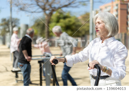 Senior woman training on outdoor gym equipment Senior woman training on outdoor gym equipment 139604013
