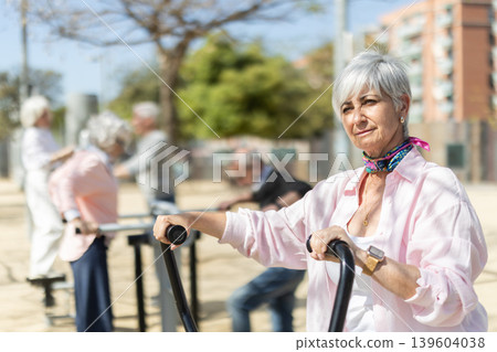 Group of elderly people exercising using equipment in courtyard Group of elderly people exercising using equipment in courtyard 139604038