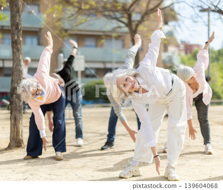 Group of elderly people perform arm swinging exercise physical activity outdoors. Group of elderly people perform arm swinging exercise physical activity outdoors. 139604068