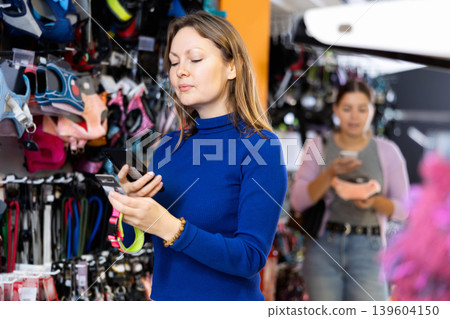 Confident woman scanning qr-code on dog harness in pet shop Confident woman scanning qr-code on dog harness in pet shop 139604150