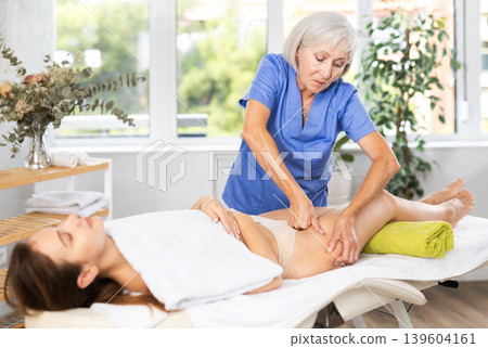 Elderly woman giving thigh massage to young woman 139604161
