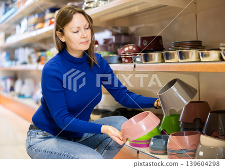 Female customer picking out bowl for pets in pet store 139604298