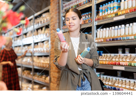 Young woman chooses bottles of paint in shop Young woman chooses bottles of paint in shop 139604441