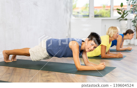 Mother, grandmother and adolescence son do exercise elbow plank pose Sampatasana. Mother, grandmother and adolescence son do exercise elbow plank pose Sampatasana. 139604524