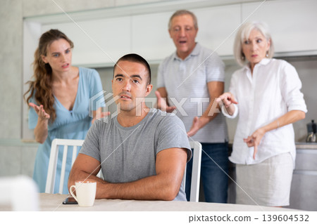 Upset and unhappy young son-in-law sitting in kitchen separately, family conflict 139604532