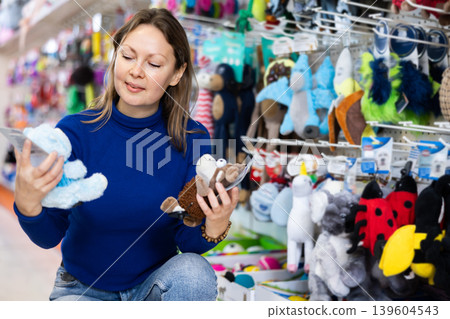 Happy woman choosing toys for pets in pet shop 139604543