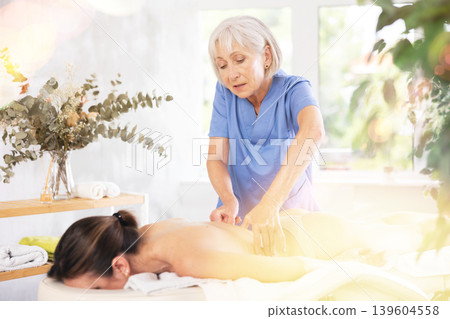 Unrecognizable young woman lies face down and enjoy lower back massage, spa body care 139604558