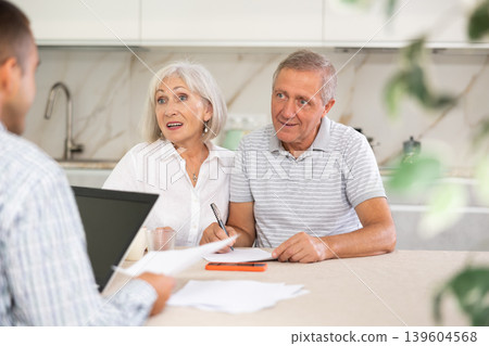 Elderly couple discussing deal with male salesman Elderly couple discussing deal with male salesman 139604568