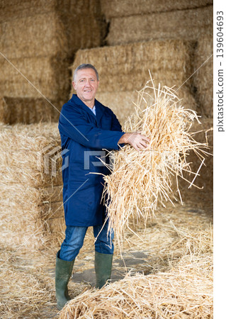 Cheerful man farmer holding bunch of hay Cheerful man farmer holding bunch of hay 139604693