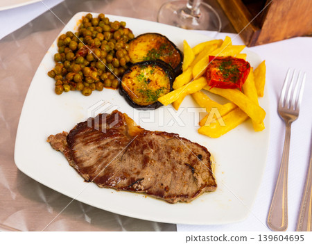 Beef steak with French fries, aubergine, peas and pesto Beef steak with French fries, aubergine, peas and pesto 139604695