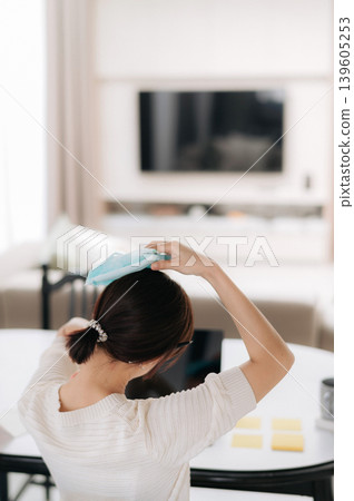 Sick asian woman suffering headache pain holding cold compress working with technology at home feeling stressed Sick asian woman suffering headache pain holding cold compress working with technology at home feeling stressed 139605253