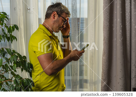 Freelancer browsing mobile phone during daytime indoors 139605328