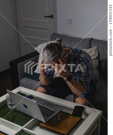 Overwhelmed remote worker sitting with laptop Overwhelmed remote worker sitting with laptop 139605342