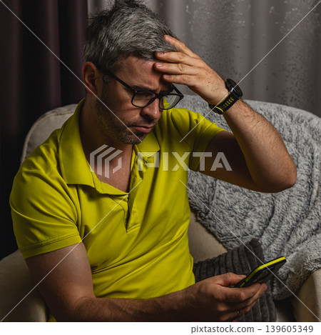 Stressed man touching forehead while using smartphone 139605349