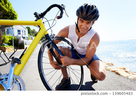 Man, portrait and wheel repair on road for safe cycling transport, performance or puncture. Male person, tyre and ocean for gear improvement or endurance for triathlon training, sport or practice Man, portrait and wheel repair on road for safe cycling transport, performance or puncture. Male person, tyre and ocean for gear improvement or endurance for triathlon training, sport or practice 139605483