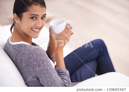Coffee, living room and portrait of Indian woman on sofa for relaxing, comfortable and calm in home. Apartment, morning and happy person with mug on couch drinking hot beverage, tea and caffeine Coffee, living room and portrait of Indian woman on sofa for relaxing, comfortable and calm in home. Apartment, morning and happy person with mug on couch drinking hot beverage, tea and caffeine 139605487