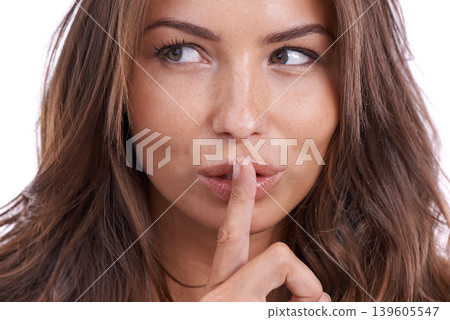 Secret, woman and face in studio for sign of privacy, confidential surprise and whisper on white background. Model thinking with finger on lips for noise, gossip and news of mystery, emoji and drama 139605547