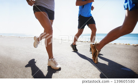 People, fitness and legs running at beach for exercise or outdoor workout together on asphalt or road. Closeup of athletic group or runners in sports, teamwork or cardio training by the ocean coast 139605580