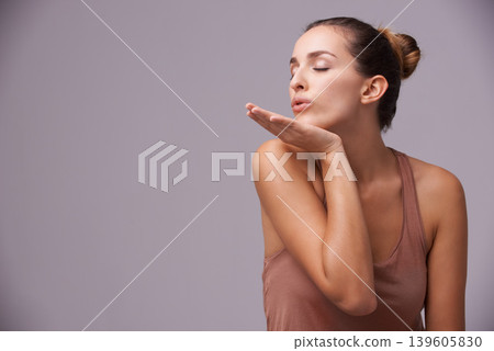 Skincare, blow kiss and young woman in studio with health, wellness and dermatology routine. Cosmetic, confident and female person with natural facial treatment and flirt gesture by gray background. Skincare, blow kiss and young woman in studio with health, wellness and dermatology routine. Cosmetic, confident and female person with natural facial treatment and flirt gesture by gray background. 139605830
