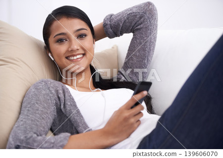 Young woman, phone and earphones, relax on couch with social media, communication and music in portrait. Listen to radio, podcast or watch video online, web or blog with mobile app and tech at home Young woman, phone and earphones, relax on couch with social media, communication and music in portrait. Listen to radio, podcast or watch video online, web or blog with mobile app and tech at home 139606070
