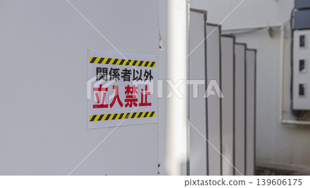 A warning sign indicating that entry is prohibited to unauthorized personnel, and a white wall. A warning sign indicating that entry is prohibited to unauthorized personnel, and a white wall. 139606175